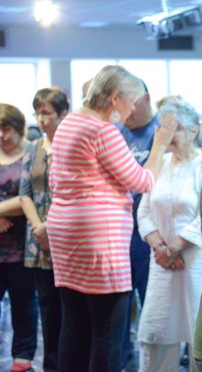 Катрина Дорон молится за женщину в общине «Тиферет Йешуа»